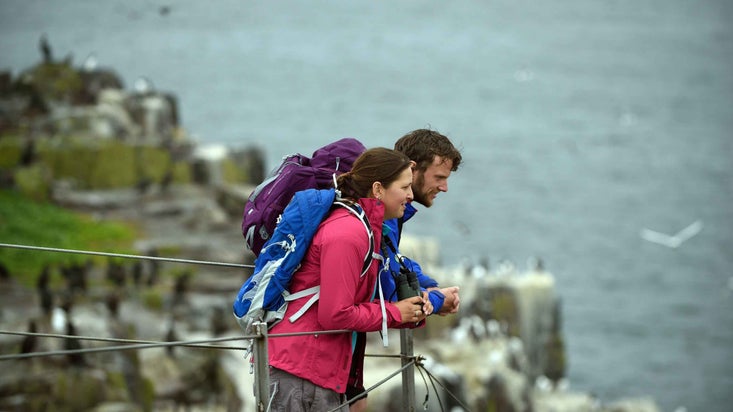 Two visitors bird watching with binoculars at the Farne Islands, Northumberland